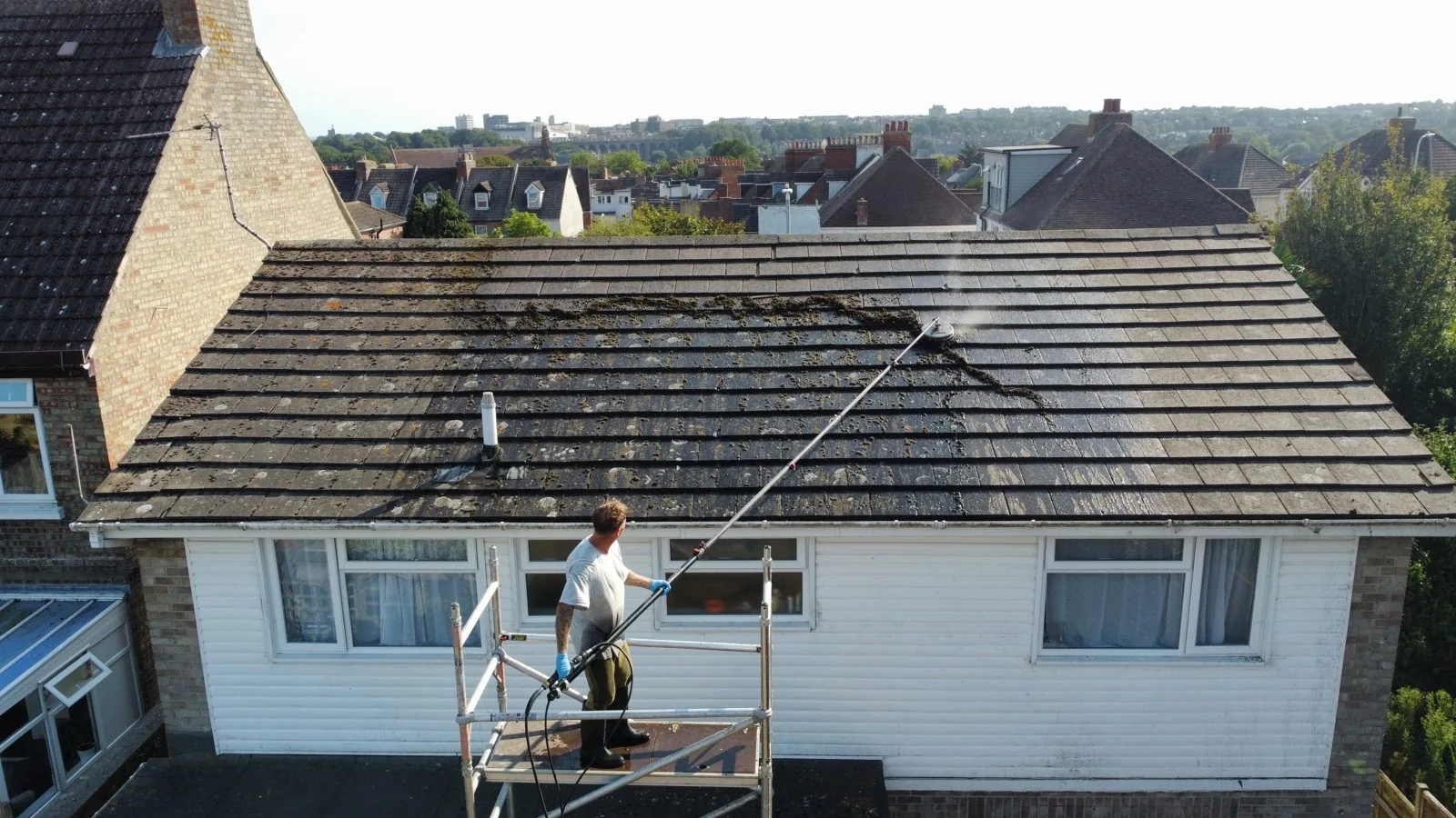Soft washing a moss-covered roof from a work platform in Folkestone